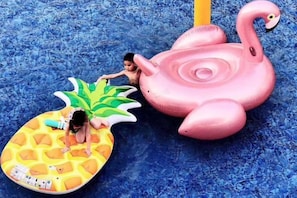 A child on a pineapple-shaped float and a pink flamingo float in a water play area. - Huidong Sumao Homestay (Xunliao Bay) (Huidong)