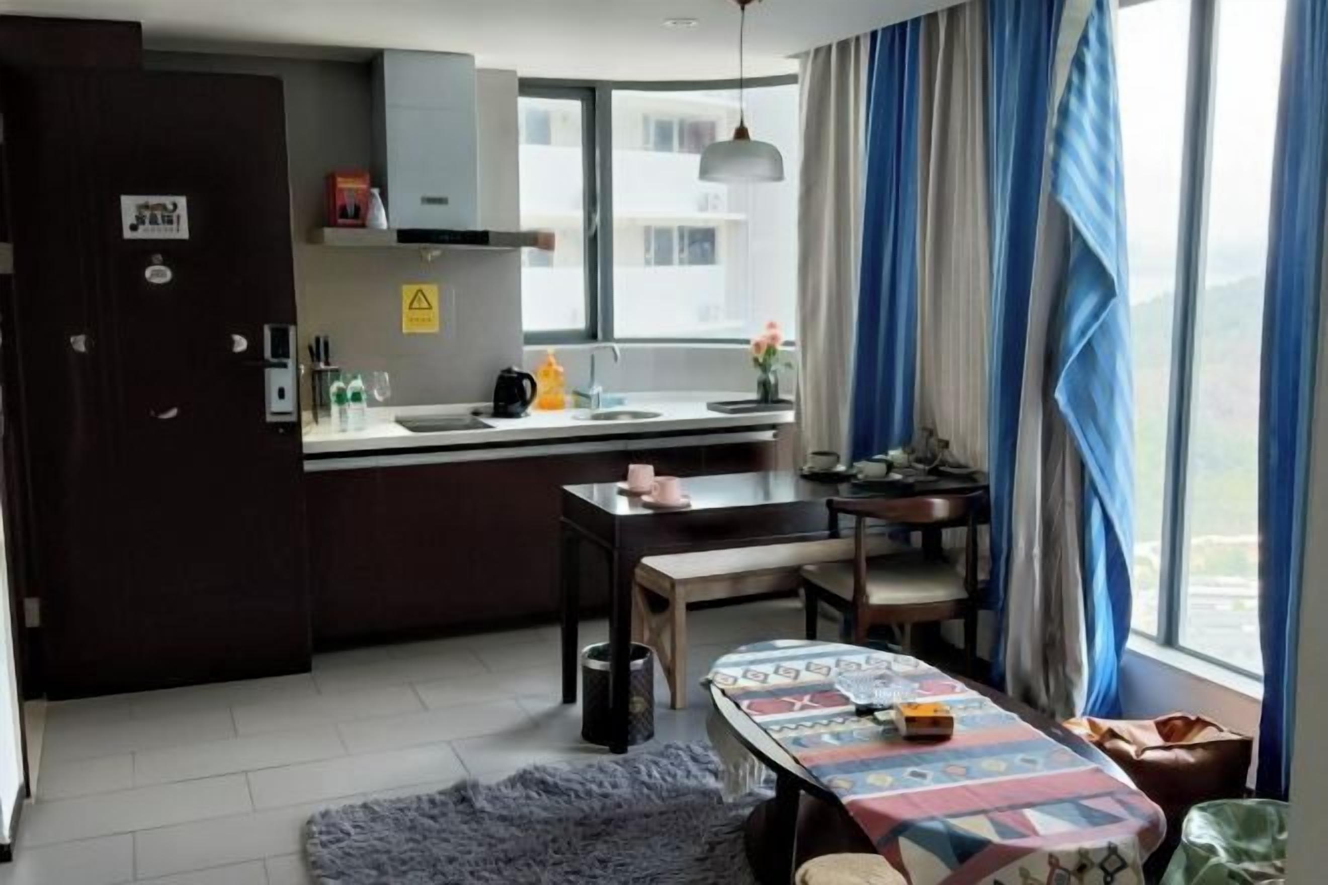 Cocina compacta con zona de comedor, ventana con cortinas y vistas a edificios.