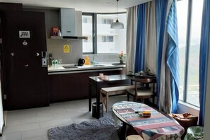 A compact kitchen with a dining area, a window with curtains, and a view of buildings outside. - Huidong Sumao Homestay (Xunliao Bay) (Huidong)