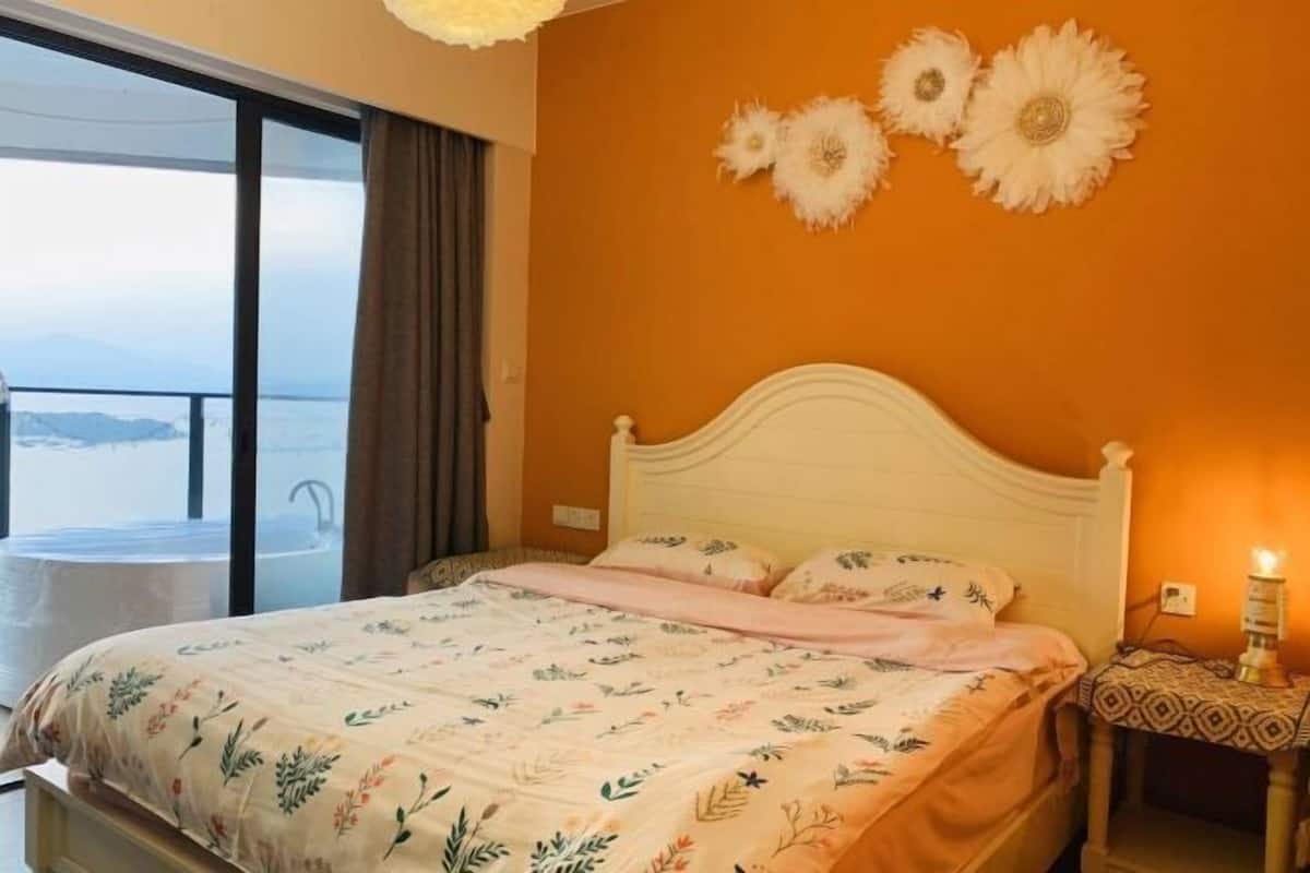 A bedroom with a bed, a nightstand, and a view of the sea.