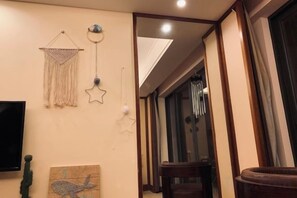 A room with a television, wall decorations including a star and a hanging macrame piece, and a wooden chair. - Huidong Sumao Homestay (Xunliao Bay) (Huidong)
