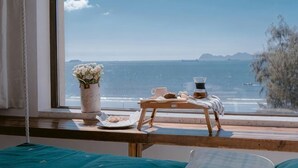A room with a view of the sea, a wooden table with a tray, a vase with flowers, and a window with a curtain. - Huidong Sumao Homestay (Xunliao Bay) (Huidong)