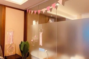 A modern bathroom with a glass partition, a decorative wall hanging, and a small bedside table with a plant. - Huidong Sumao Homestay (Xunliao Bay) (Huidong)