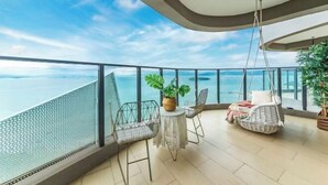 A balcony with a view of the sea, a hanging chair, a small table, and a potted plant. - Huidong Sumao Homestay (Xunliao Bay) (Huidong)