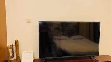 A television on a wooden stand in a room with a bed and a small wooden structure.