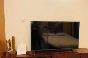 A television on a wooden stand in a room with a bed and a small wooden structure. - Huidong Sumao Homestay (Xunliao Bay) (Huidong)