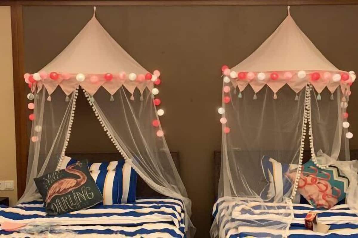 Two beds with striped bedding and canopy tents with hanging decorations.
