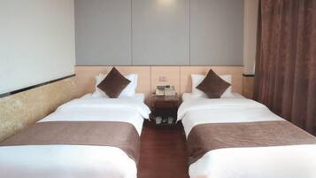 A hotel room with two single beds, a nightstand, and a large wardrobe.
