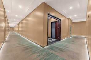 A hotel corridor with a carpeted floor, a door leading to a room, and a wall-mounted elevator. - Bin Huilanting Hotel (Ma'anshan High-Speed Rail East Station) (Ma'anshan)