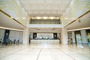 A spacious lobby with a reception desk, seating area, and a second-floor balcony.