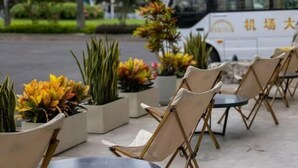 Outdoor seating with chairs and planters, a white van, and a building in the background. - Shenzhen Airport Hotel(Shenzhen Bao'an International Airport T3 Terminal Store) (Shenzhen)