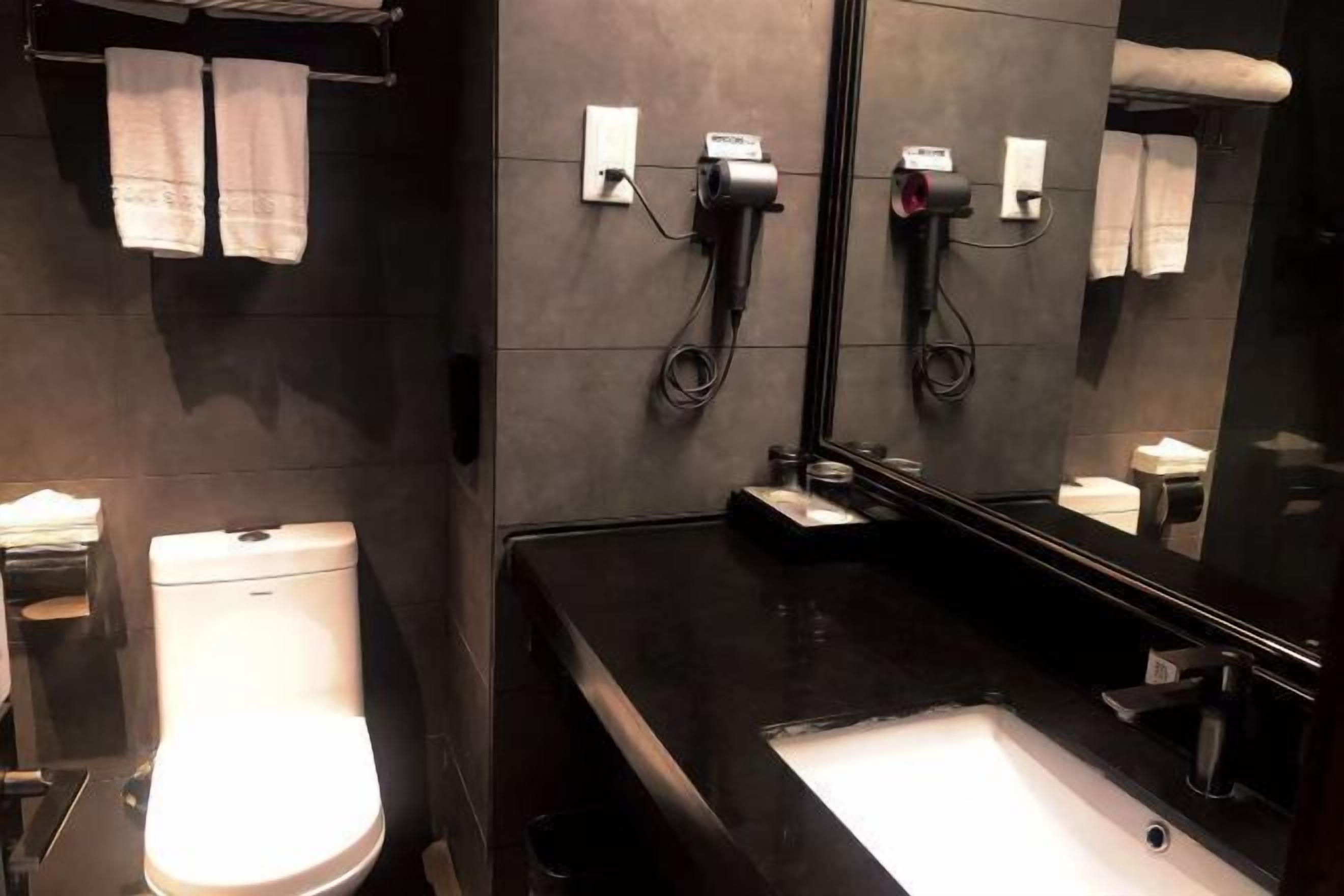 A modern bathroom with a toilet, sink, and towel rack.