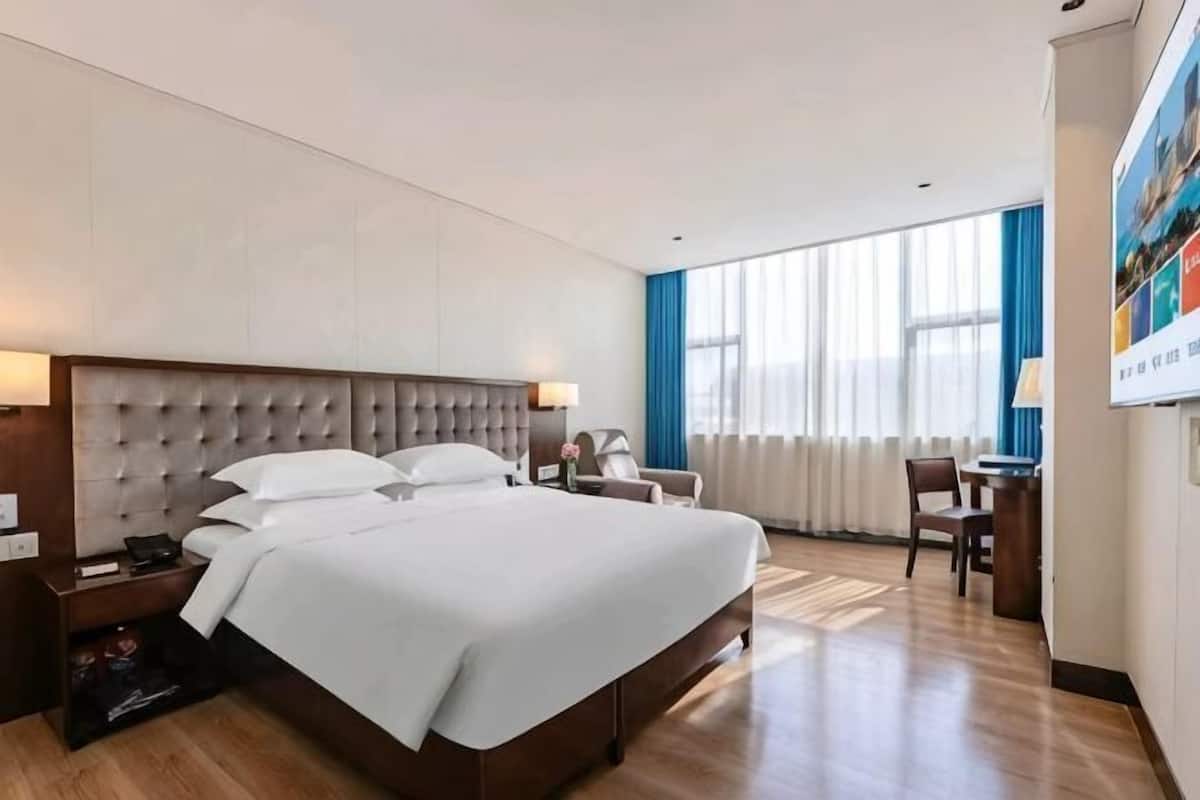 A hotel room with a large bed, a desk, and a chair.