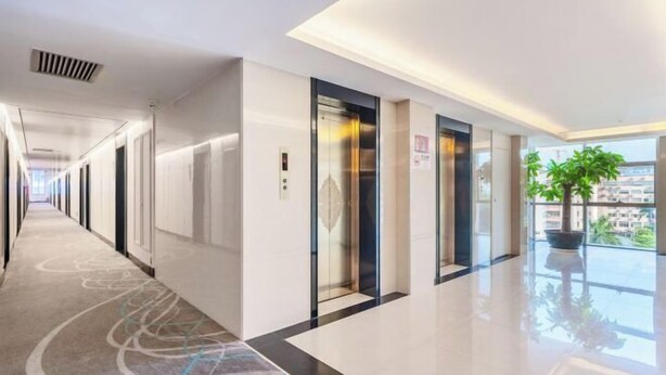 A hotel corridor with a modern design, including a glass elevator, a potted plant, and a view of the outside. - Shenzhen Airport Hotel(Shenzhen Bao'an International Airport T3 Terminal Store) (Shenzhen)