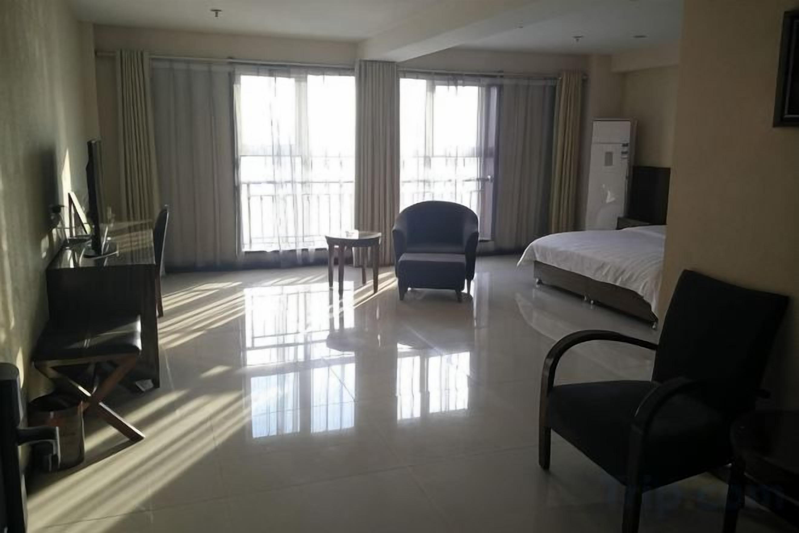 A hotel room with a bed, a desk, a chair, and a TV.
