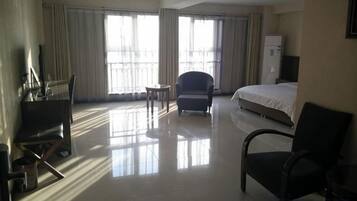 A hotel room with a bed, a desk, a chair, and a TV.