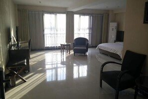Une chambre d’hôtel avec un lit, un bureau, une chaise et un téléviseur.
