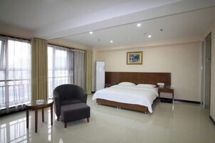 Una habitación de hotel con una cama grande, una silla, una mesita pequeña y una mesita de noche.