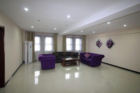 A spacious living room with a sofa set, a coffee table, and two purple armchairs. - Longdu Business Hotel (Zhaoyuan)