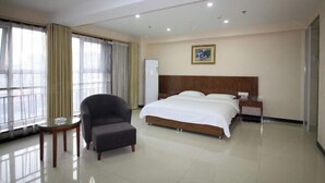 A hotel room with a large bed, a chair, a small table, and a painting on the wall. - Longdu Business Hotel (Zhaoyuan)