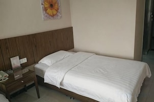Una cama individual con cabecera de madera, una mesita de noche con lámpara y una decoración floral en la pared.