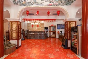 Un hall de hotel con mostrador de recepción, refrigerador y techo decorativo.