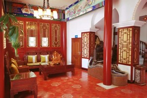 A traditional interior with a red floor, wooden furniture, and decorative screens. - Xingyu Hotel (Beijing Daxing Caiyu Branch) (Beijing)