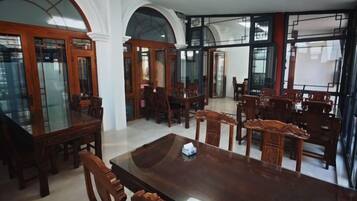 A spacious dining area with a large wooden table and multiple chairs, surrounded by arched windows and doors.