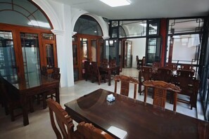 A spacious dining area with a large wooden table and multiple chairs, surrounded by arched windows and doors. - Xingyu Hotel (Beijing Daxing Caiyu Branch) (Beijing)