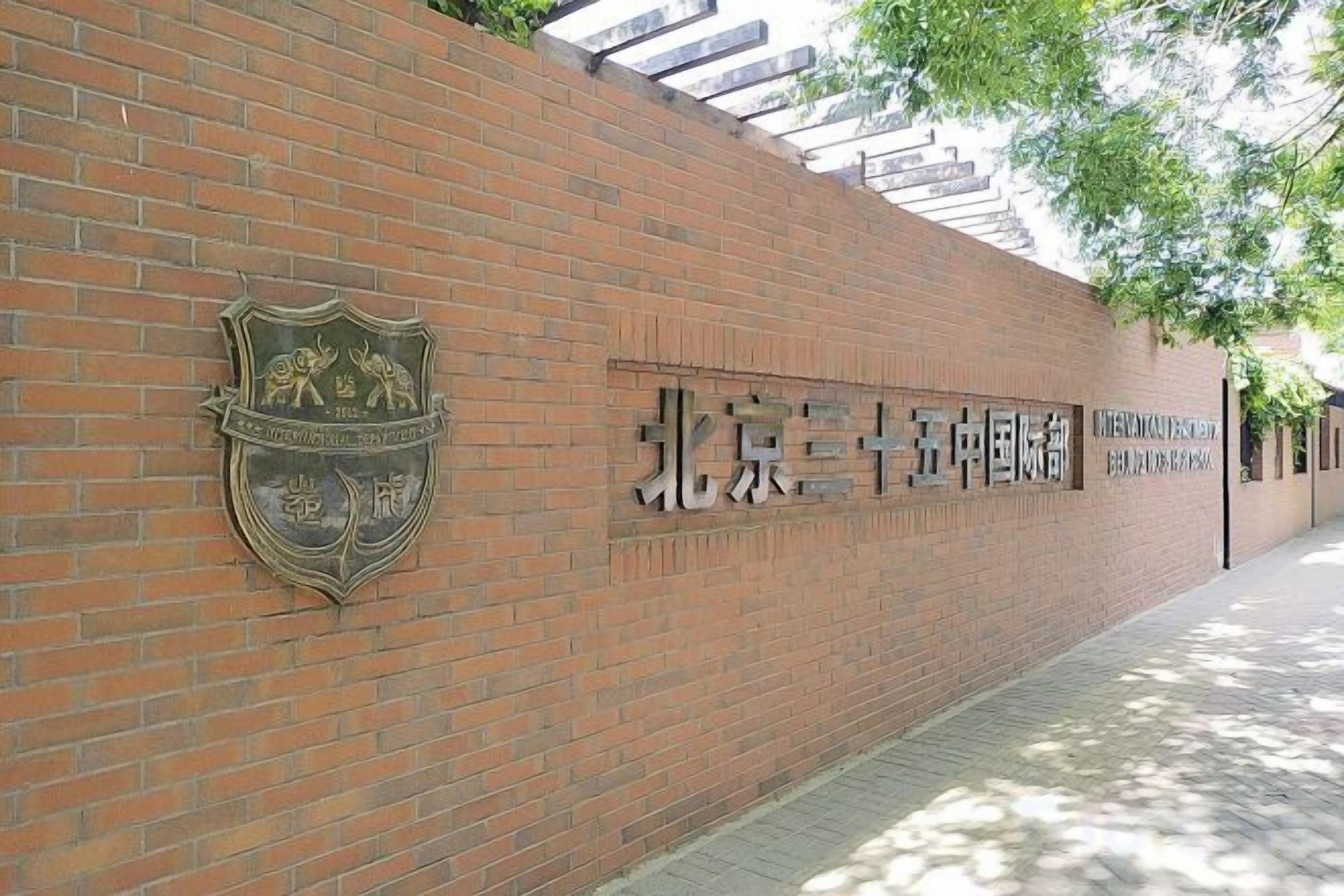 A brick wall with a crest emblem and Chinese characters, indicating a university entrance.
