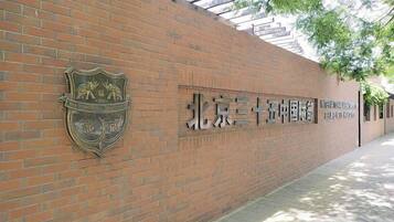 A brick wall with a crest emblem and Chinese characters, indicating a university entrance.