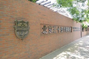 A brick wall with a crest emblem and Chinese characters, indicating a university entrance. - Xingyu Hotel (Beijing Daxing Caiyu Branch) (Beijing)