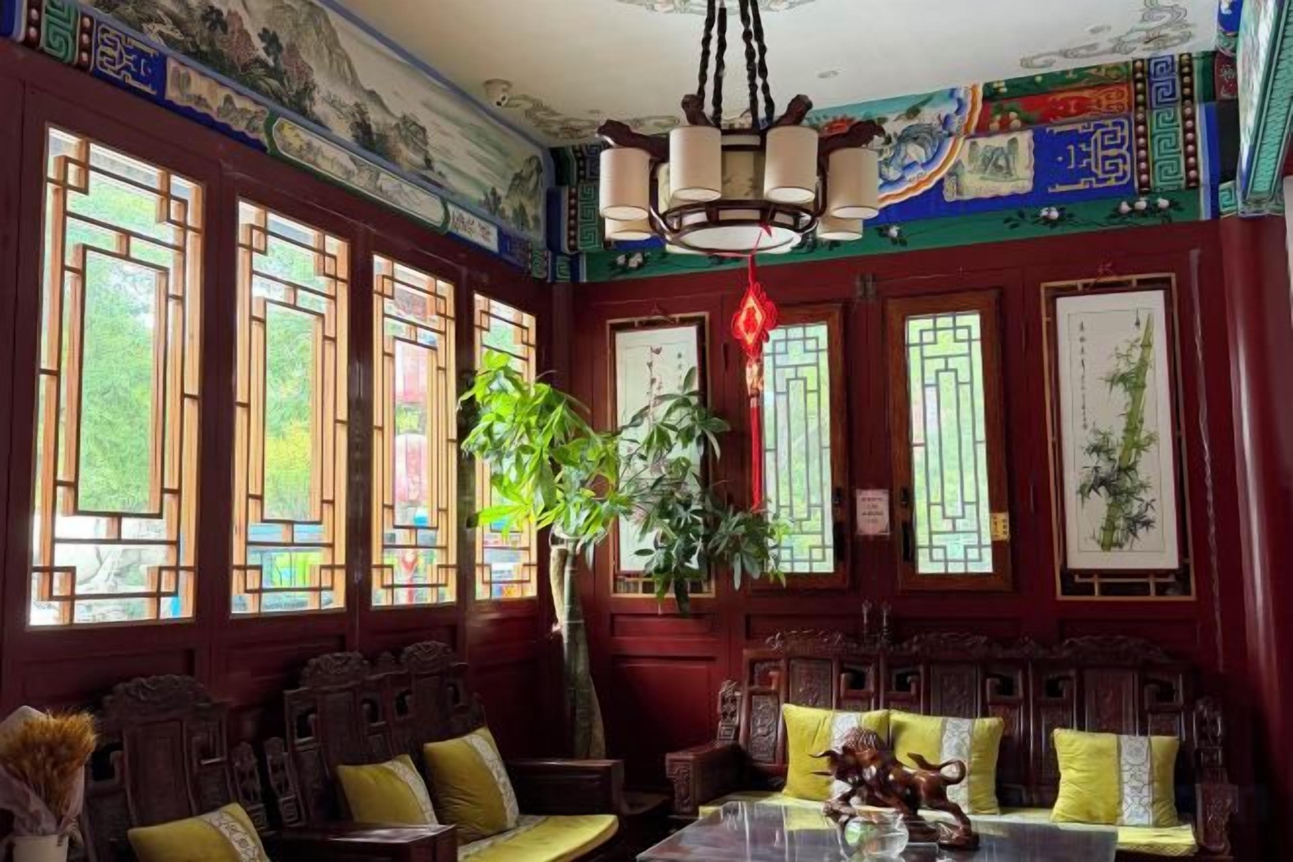 A traditional room with wooden furniture, large windows with decorative glass, and a hanging light fixture.