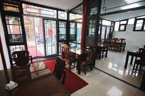 A dining area with tables and chairs, large windows with a view, and a red carpet. - Xingyu Hotel (Beijing Daxing Caiyu Branch) (Beijing)