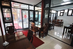 A dining area with tables and chairs, large windows with a view of the street, and a red carpet. - Xingyu Hotel (Beijing Daxing Caiyu Branch) (Beijing)