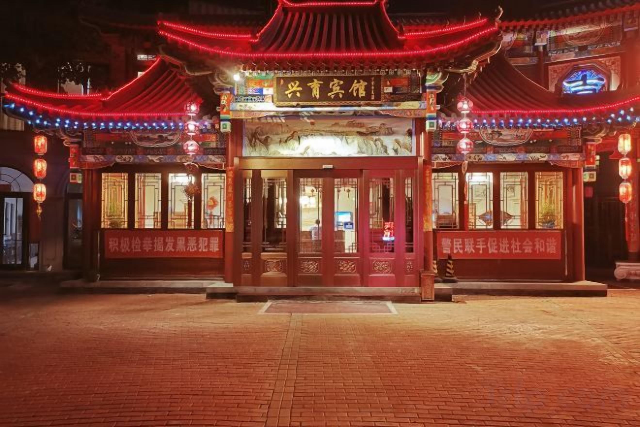 A traditional Chinese building with a red entrance and illuminated signage.