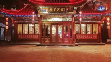 A traditional Chinese building with a red entrance and illuminated signage.