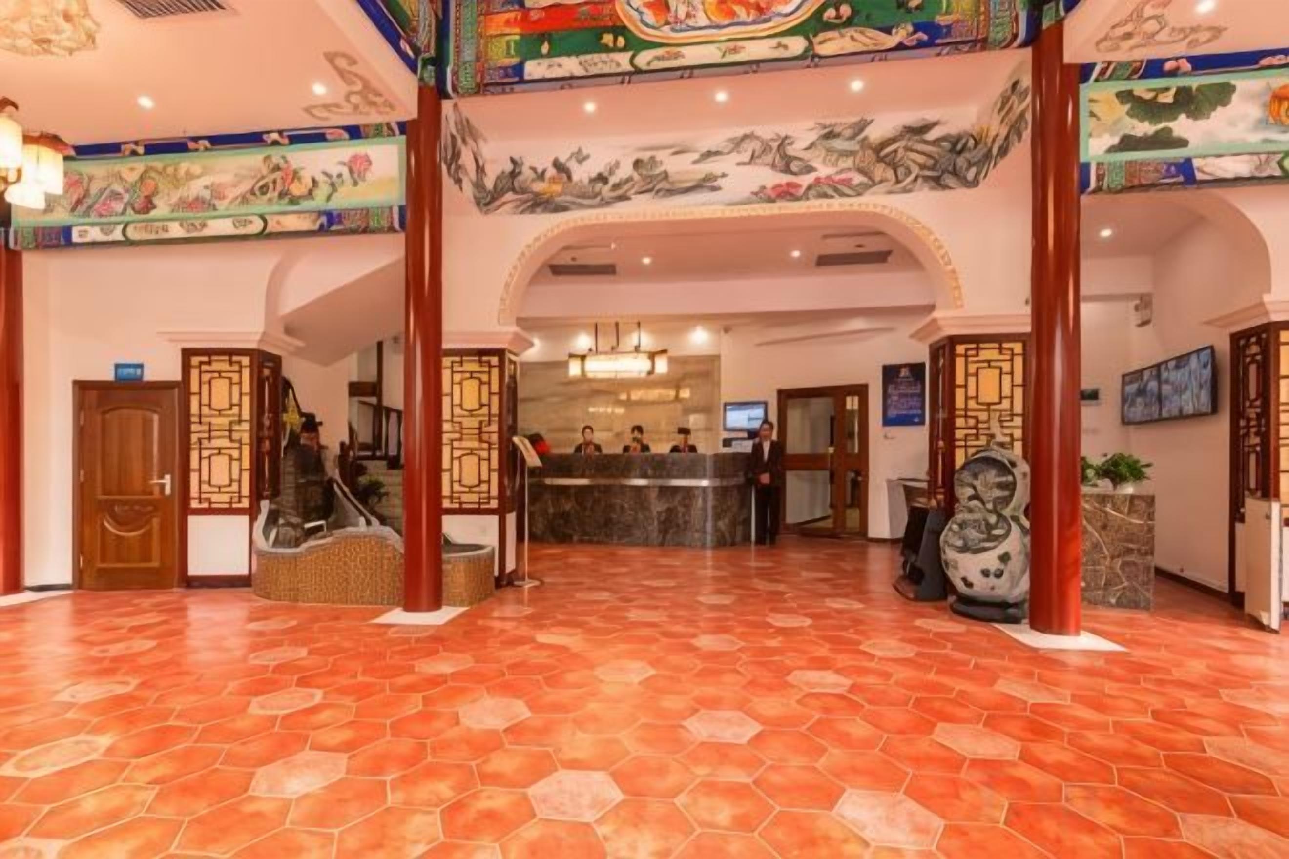 Un hall de hotel con una recepción, una escalera y decoración tradicional.