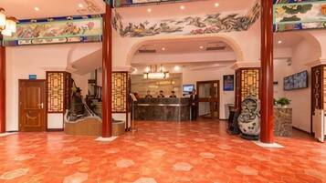 Un hall de hotel con una recepción, una escalera y decoración tradicional.