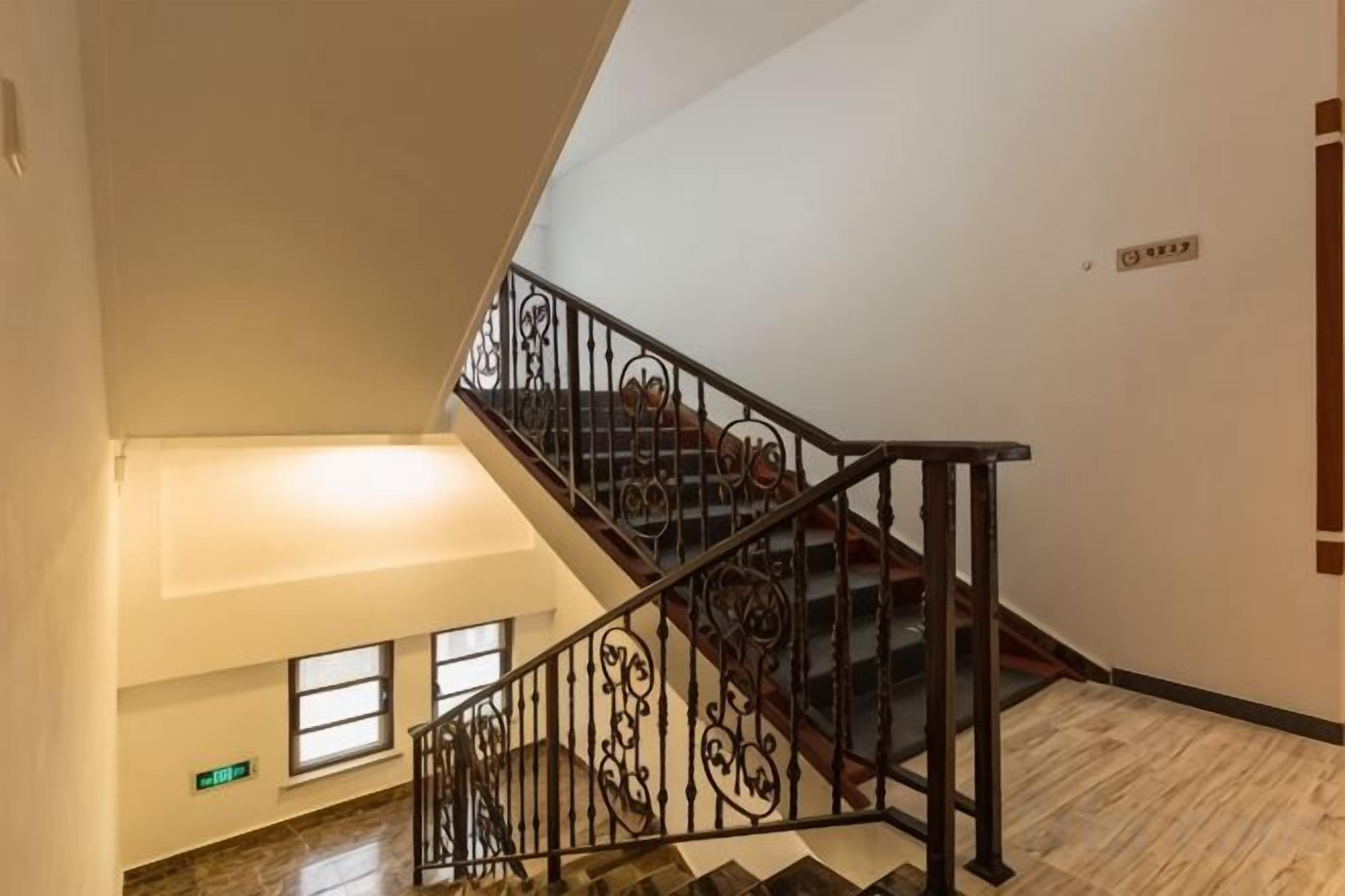 A staircase with ornate metal railings and a wooden handrail, leading to an upper floor.