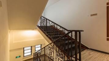 A staircase with ornate metal railings and a wooden handrail, leading to an upper floor.