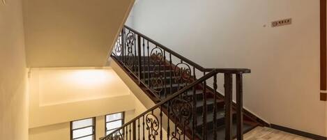 A staircase with ornate metal railings and a wooden handrail, leading to an upper floor.