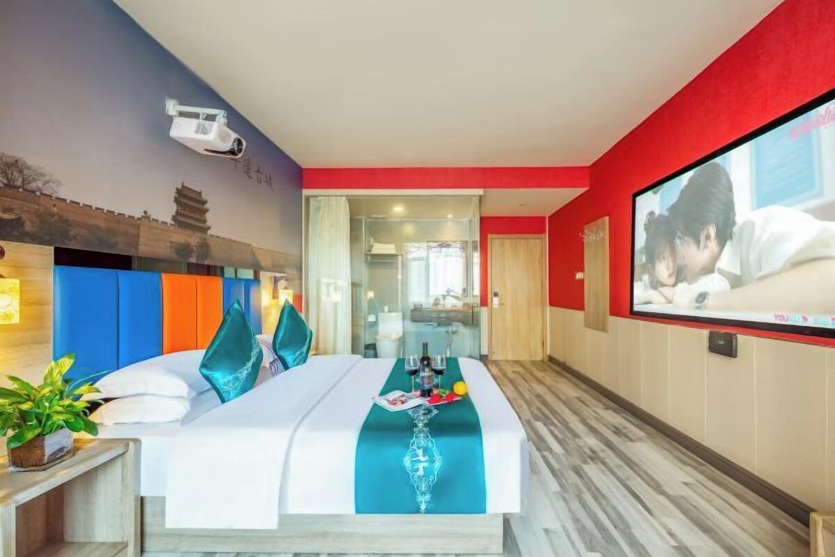 A hotel room with a bed, a TV, a desk, and a window.