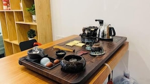 Une table en bois sur laquelle se trouve un plateau contenant des ustensiles à thé, une bouilloire et une petite plante.