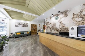 A reception area with a wooden reception desk, a green sofa, and a world map on the wall.
