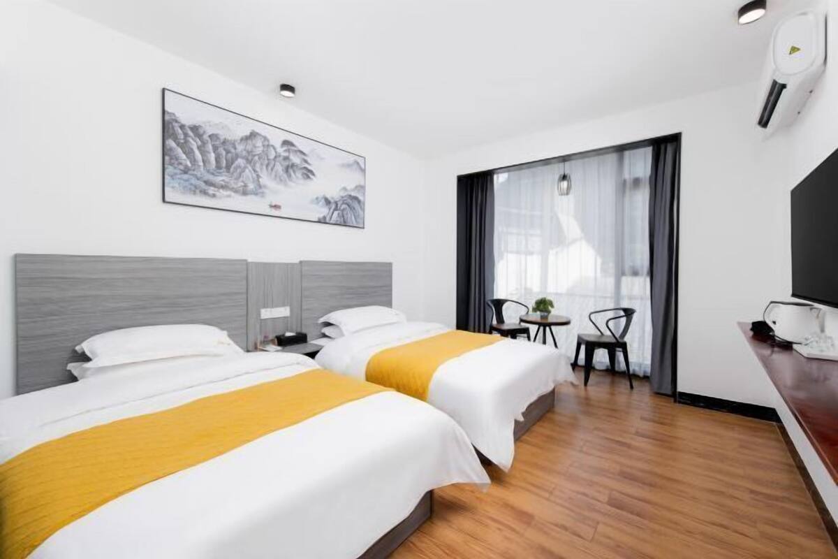 Ein Hotelzimmer mit zwei Betten, einem Gemälde, einem Schreibtisch und einem Sessel.