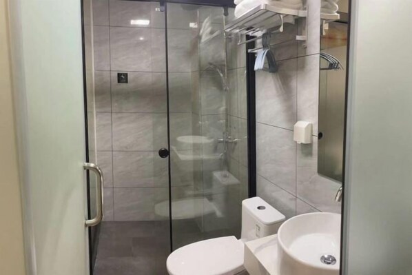 A modern bathroom with a glass-enclosed shower, a toilet, and a sink.