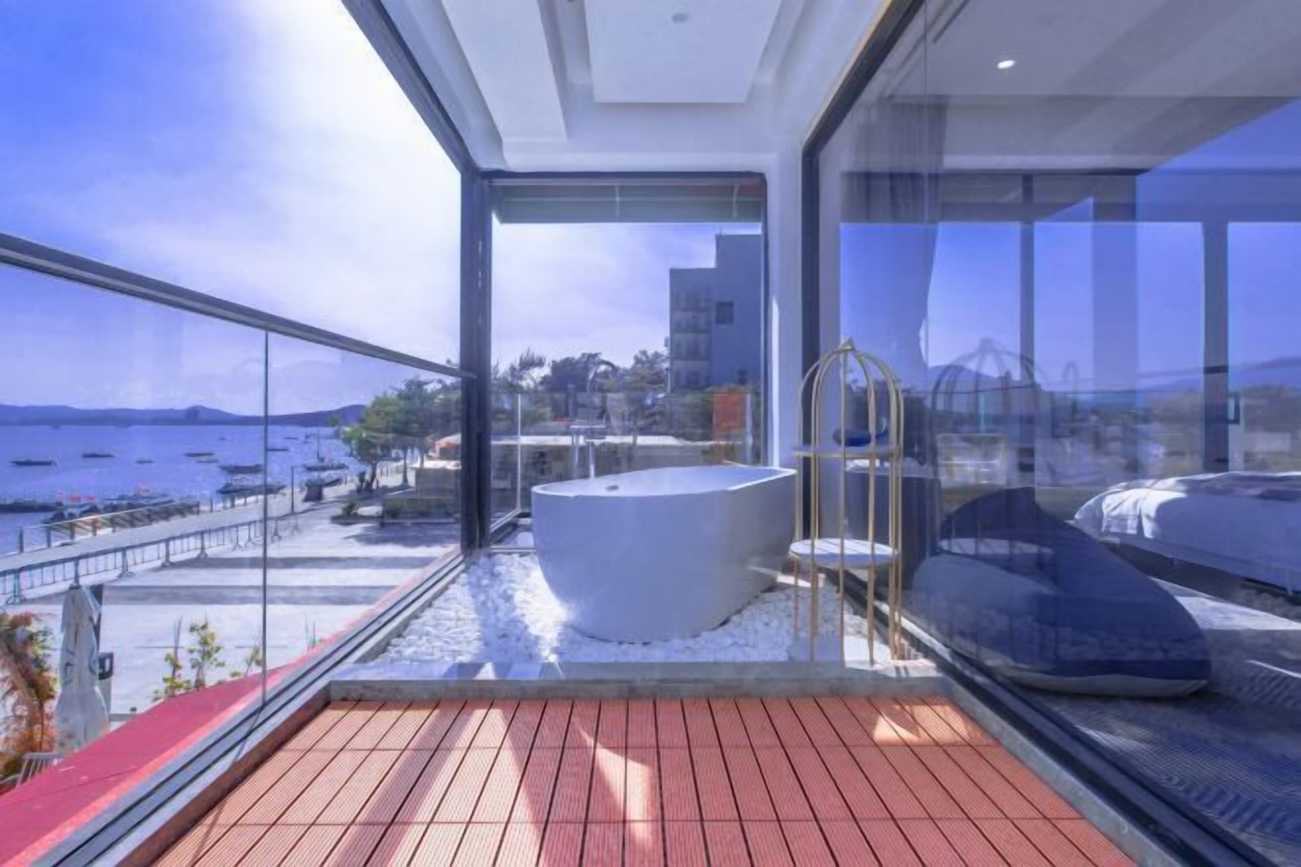 Ein moderner Balkon mit Meerblick, einer großen weißen Badewanne und einer Glasumlaufung.
