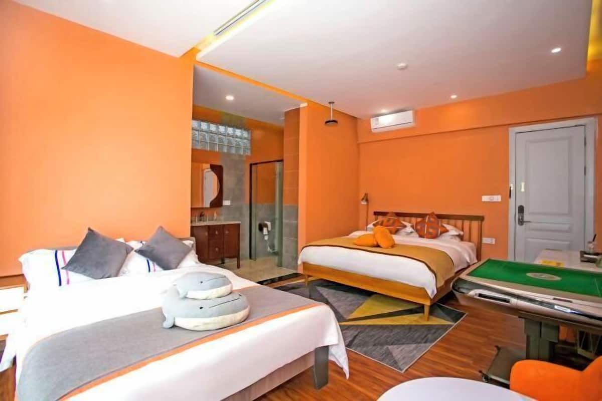 A hotel room with two beds, a desk with a pool table, and a bathroom visible through a glass door.