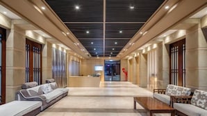 Eine Hotelhalle mit Empfangstresen, Sitzbereichen und modernem Deckenstil.